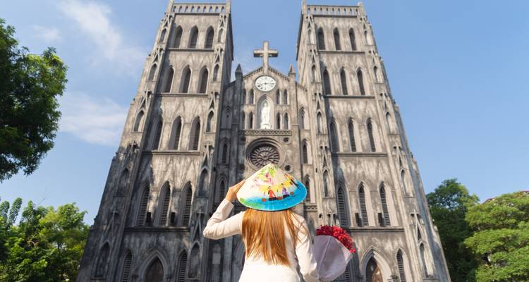 Dos d'une femme avec un chapeau conique regardant une cathédrale.
