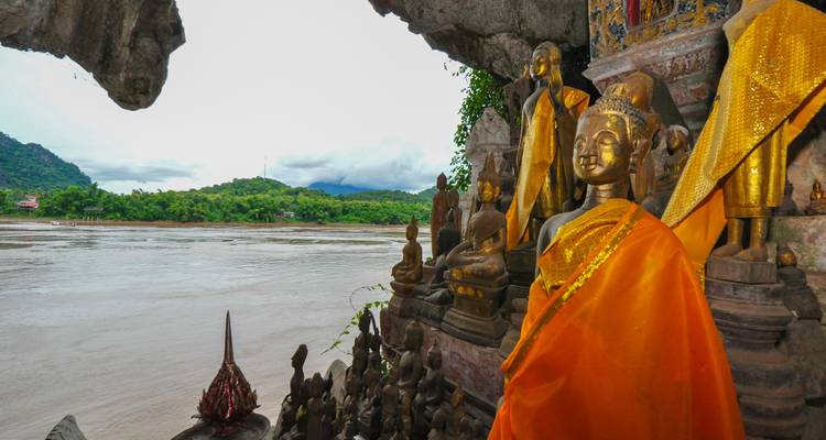 Statues de Bouddha à l'intérieur d'une grotte surplombant une rivière.