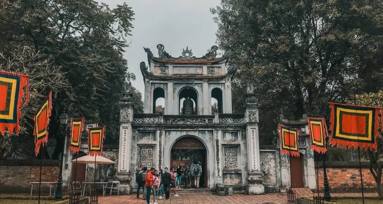 People walking in front of an ancient temple gate.