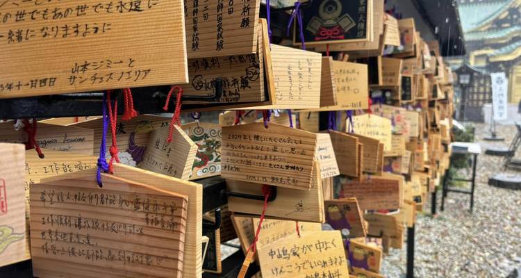 Wooden ema plaques covered in handwritten wishes hang densely at a Shinto shrine walkway