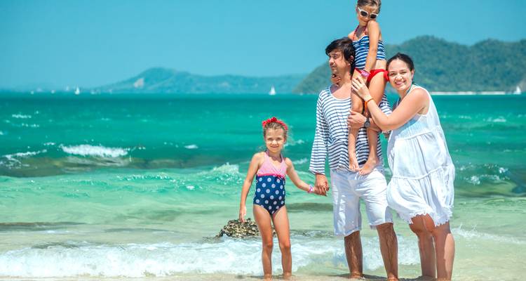 Familie posiert glücklich an einem sonnigen Strand.