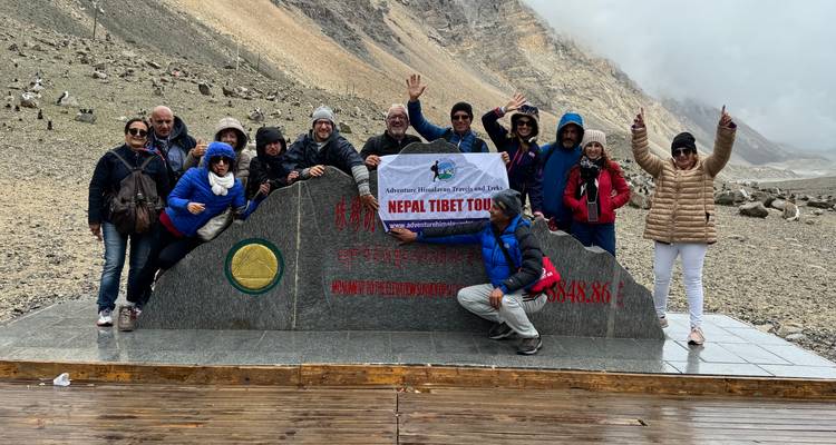 Groupe de personnes posant derrière un panneau de voyage Népal Tibet.
