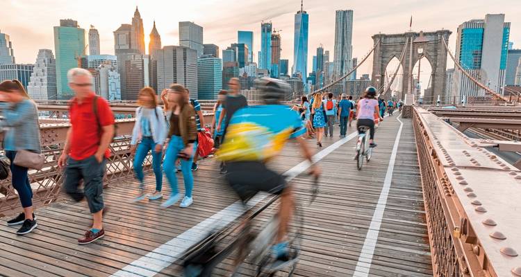 Mensen die lopen en fietsen op een brug met een stadshorizon.