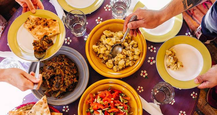 People sharing Moroccan dishes on a table.