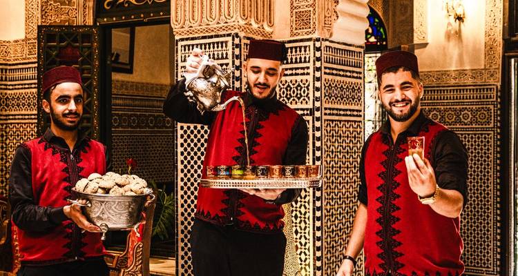 Personnel de service servant le thé marocain traditionnel et des pâtisseries.