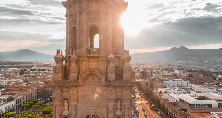 Großes historisches Gebäude mit Bergkulisse und Sonnenuntergangslicht.