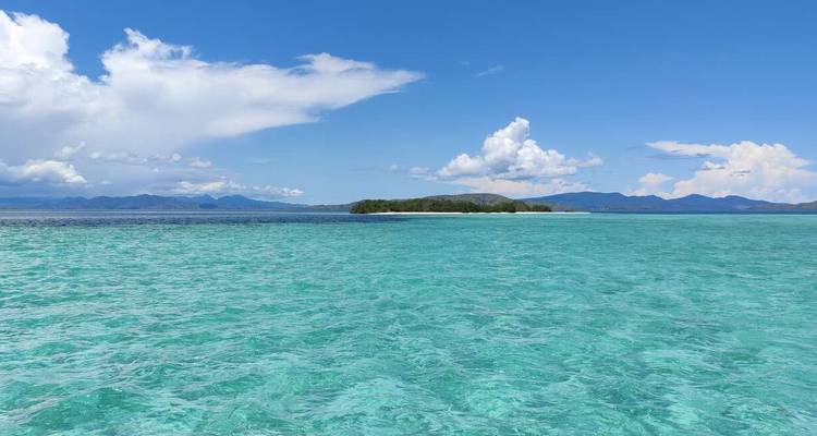 Weites türkisfarbenes Meer mit entfernter Insel unter klarem Himmel.