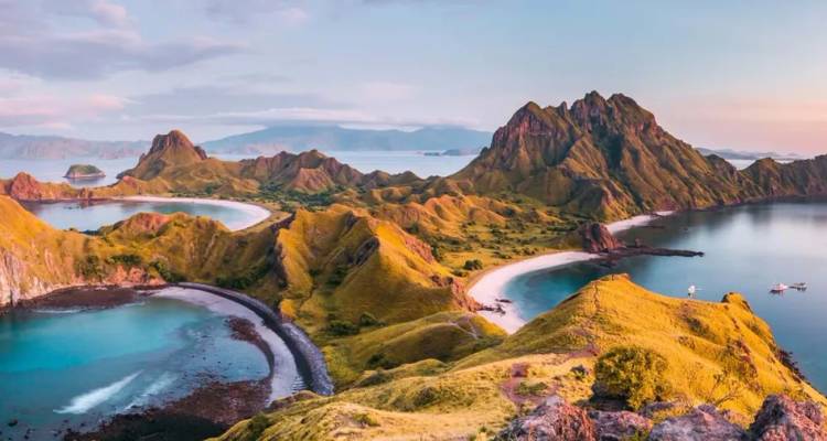 Vue aérienne spectaculaire de l'île de Padar avec ses baies sinueuses, ses eaux turquoise et ses crêtes verdoyantes escarpées au lever du soleil.