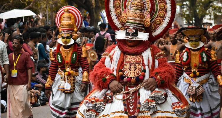 Artistas tradicionales con trajes elaborados participando en un desfile cultural.