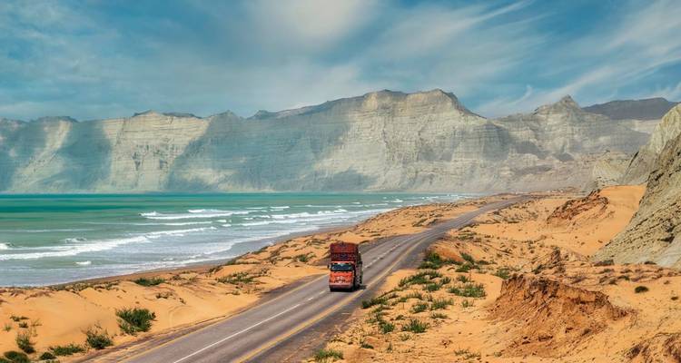 Schilderachtige kustweg met bergen en een vrachtwagen.