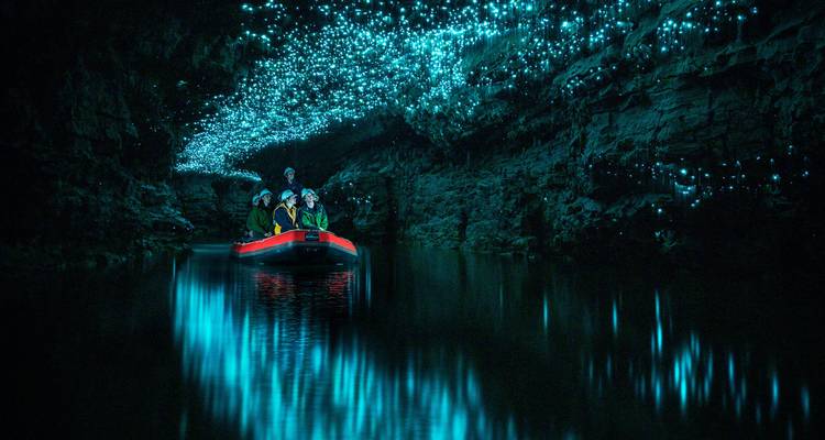 Grotte aux vers luisants créant une ambiance bleue magique au-dessus d'une rivière souterraine.
