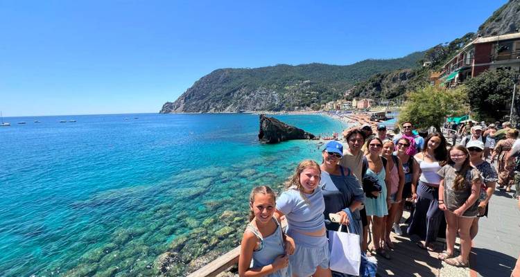 Photo de groupe de personnes près d'une mer bleu clair avec une côte rocheuse.