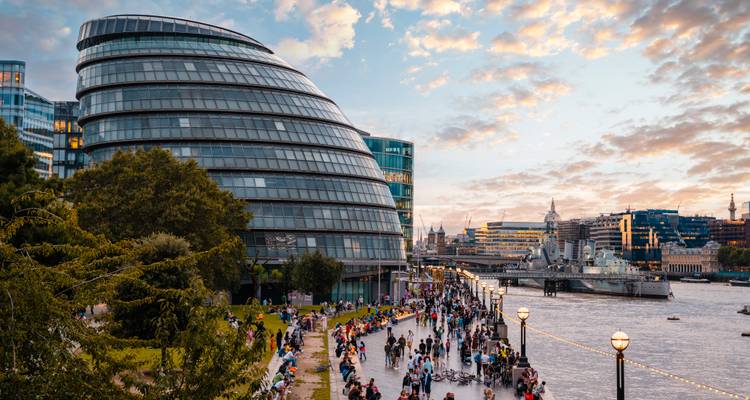 Rivierwandeling met moderne gebouwen en avondmenigte.