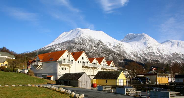 Casas tradicionales noruegas con montañas nevadas de fondo.