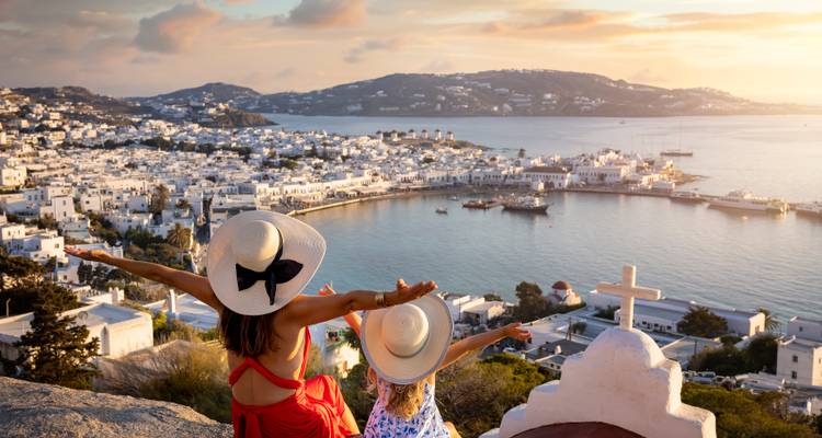 Zwei Personen mit erhobenen Armen, die eine malerische Bucht überblicken.