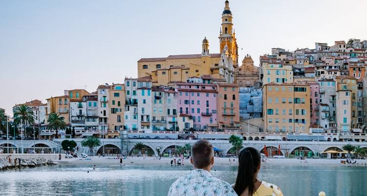 Stel zittend met het gezicht naar een stad met kleurrijke huizen aan zee.