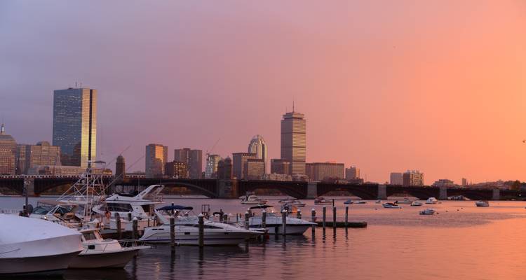 Vista del atardecer del horizonte de Boston con yates atracados en el río Charles.