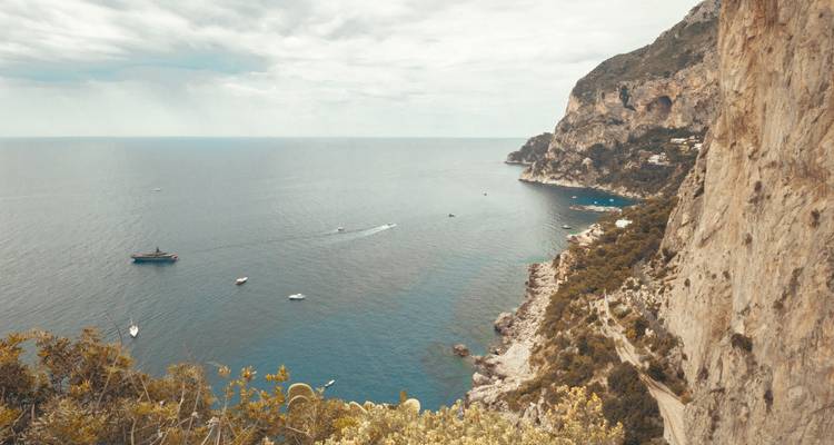 Luftaufnahme einer Klippenküste mit Booten im Wasser.