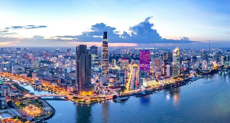 Aerial view of Ho Chi Minh City at dusk with illuminated skyscrapers.