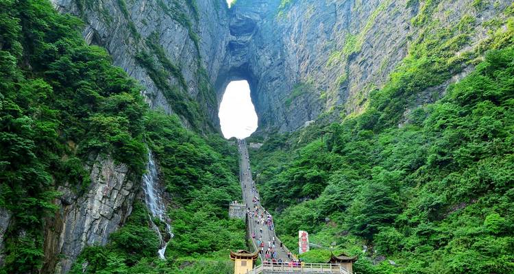 Steile Treppe, die zum Himmeltor des Tianmen-Berges führt und von aufragenden Klippen und üppiger Vegetation eingerahmt wird.