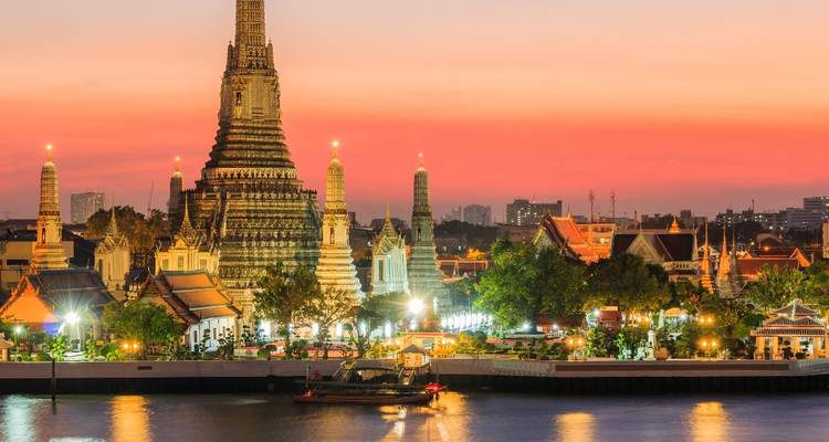 Icónico templo Wat Arun y el horizonte de la ciudad brillando con una puesta de sol rosa vibrante sobre el río Chao Phraya.