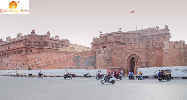 Historische Festung in einer Stadtstraße mit Menschen auf Fahrzeugen.