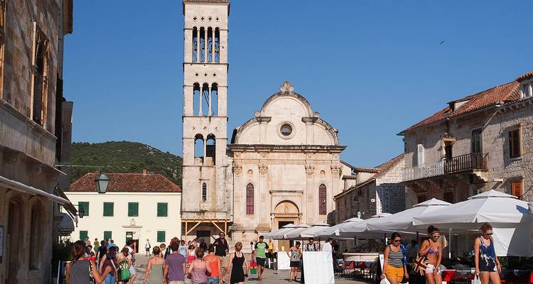 Historischer Platz mit einer markanten Kirche und gehenden Menschen