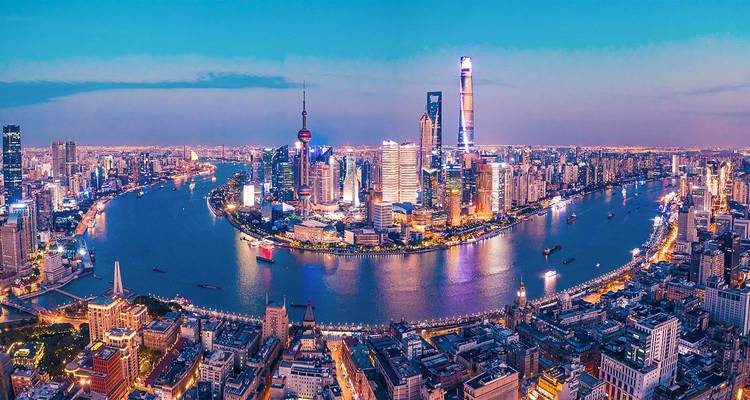 Vue panoramique en soirée de la ligne d'horizon de Shanghai avec des gratte-ciel scintillants s'incurvant le long du fleuve Huangpu