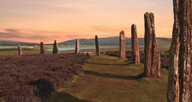 Les anciens menhirs du cercle de Brodgar brillent sous un coucher de soleil pastel dans les Orcades.