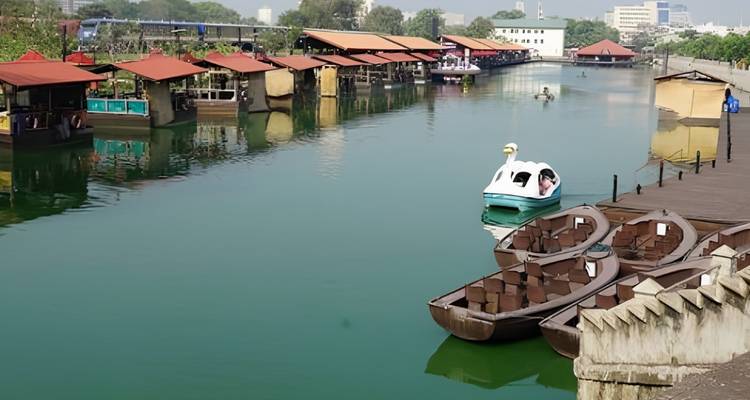 Rustig groen kanaal omzoomd met kleine paalwoningen en roeibootjes, met een eenzame persoon in een zwaan-trapboot