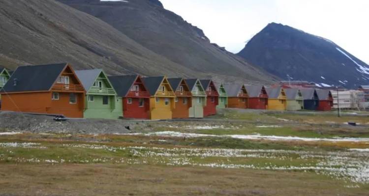 Rij kleurrijke houten huizen genesteld onder kale Arctische heuvels