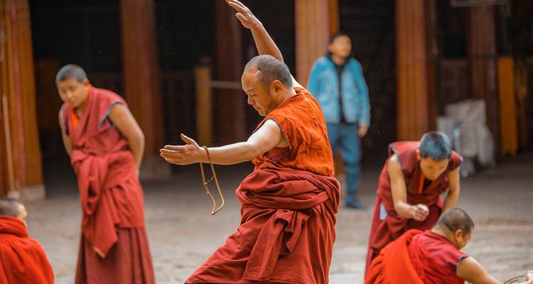 Monjes tibetanos con túnicas se dedican a un animado debate en el patio de un monasterio.