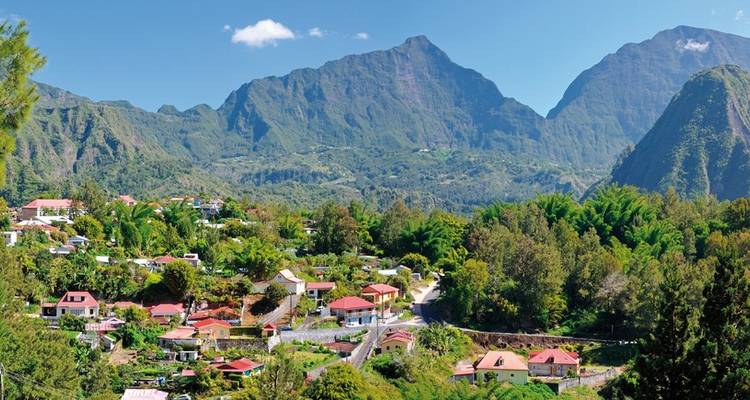 Village de montagne pittoresque aux toits colorés situé sous des pics verdoyants imposants dans un ciel bleu éclatant