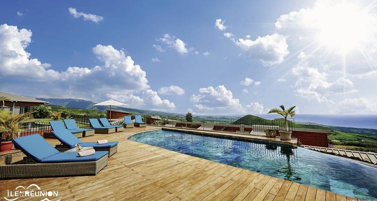 View of a pool with lounge chairs and a scenic backdrop.
