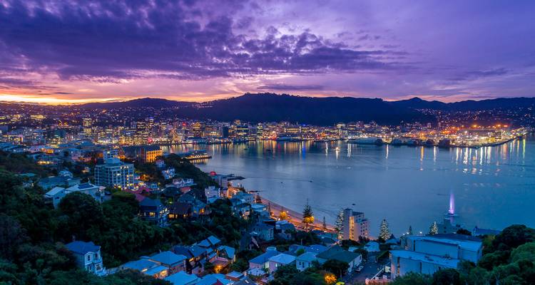 Vue panoramique d'une ville surplombant une baie au coucher du soleil.