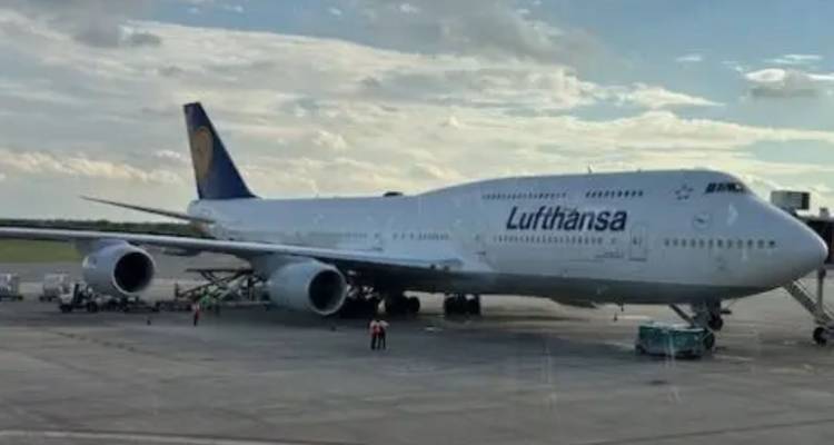 Großes Lufthansa Boeing 747 Flugzeug geparkt an einem Flughafengate unter einem teilweise bewölkten Himmel.