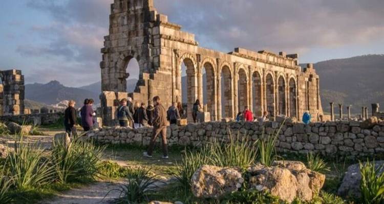 Ruines d'une cité romaine avec des touristes explorant le site.