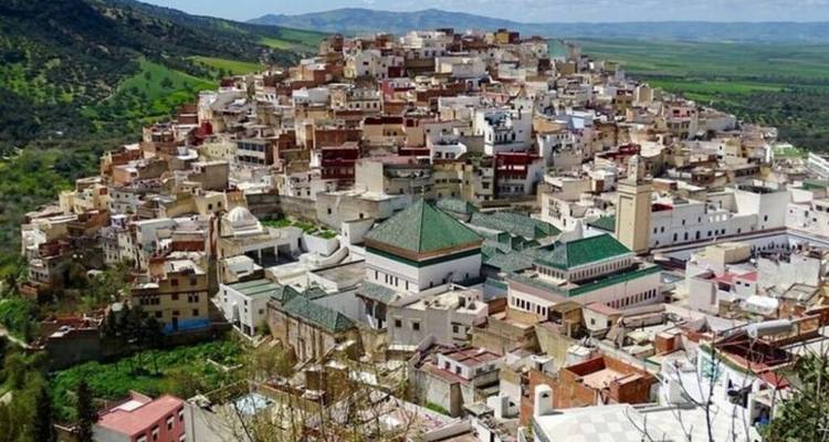 Vue aérienne d'une ville perchée densément construite avec un environnement verdoyant.