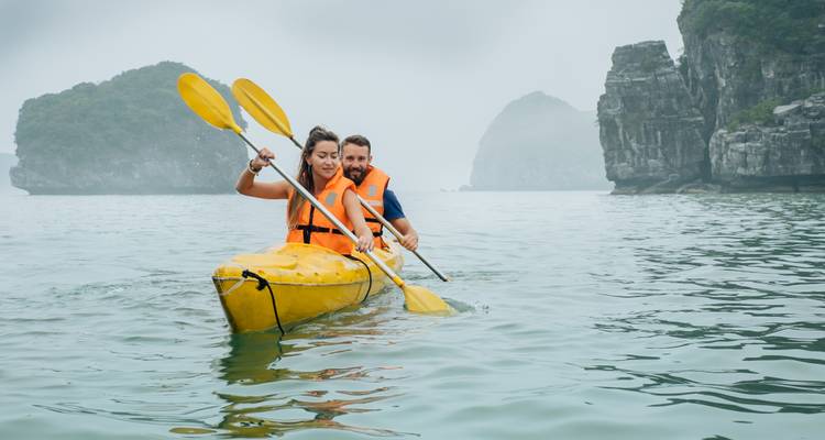 Couple kayaking in the calm waters of Halong Bay with karst formations.