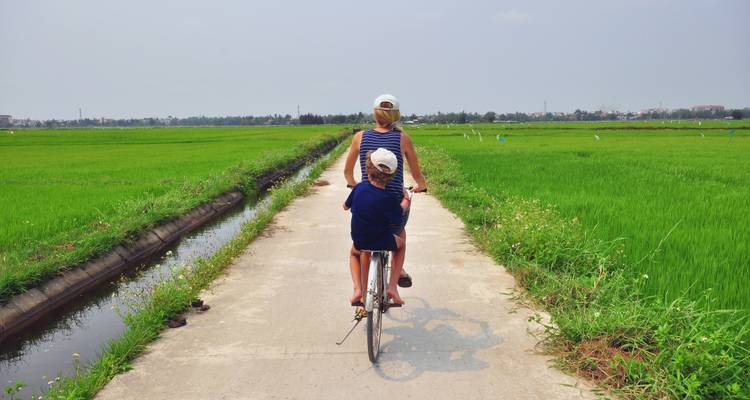 Twee mensen die fietsen door groene velden in Vietnam.