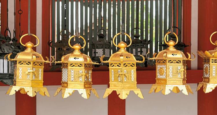 Goldene Tempellaternen vor einem traditionellen japanischen Hintergrund.