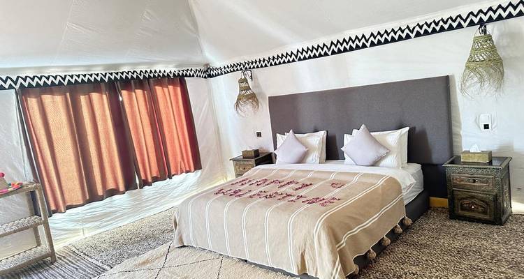 Luxuszelt-Innenraum mit einem Kingsize-Bett und moderner Einrichtung.