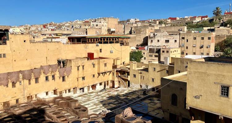Panoramablick über die historische Chouara-Gerberei in Fes mit Bottichen und erdfarbenen Gebäuden.