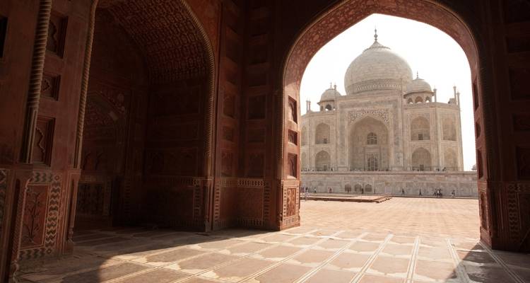 View of the Taj Mahal from inside an archway with people in the distance.