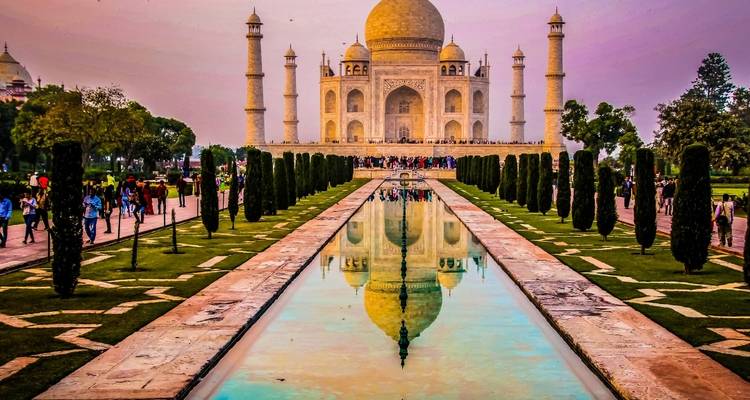 Taj Mahal reflected in the water with vibrant colors at sunset.