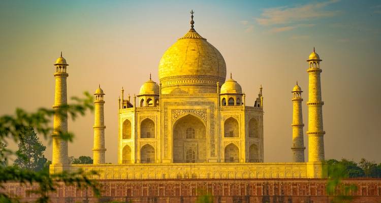 Taj Mahal under a clear sky surrounded by greenery.
