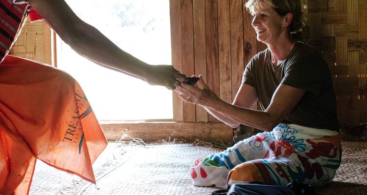Two people exchanging a cup inside a traditional wooden building.