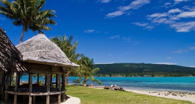 Beachfront with a traditional gazebo and palm trees in Samoa.