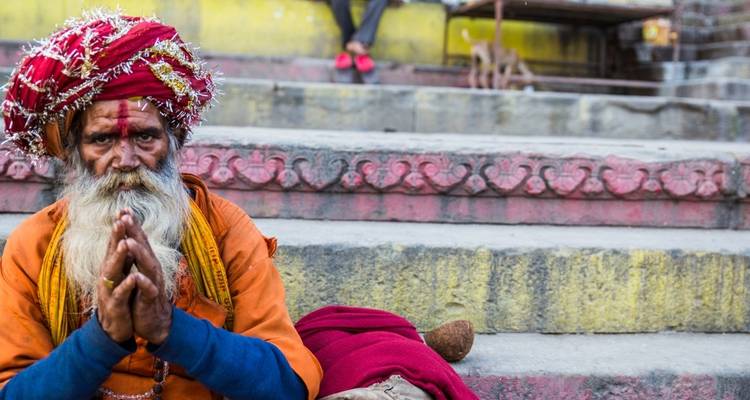 Porträt eines Mannes in traditioneller Kleidung, der auf Stufen sitzt.