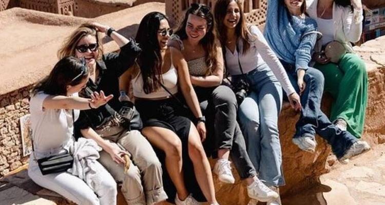 Gruppe junger Frauen, die zusammen auf einer Steinbank sitzen.